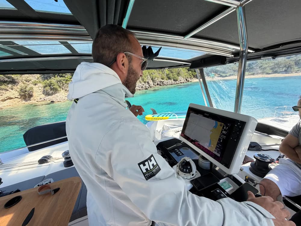Skipper navigates a boat through turquoise waters