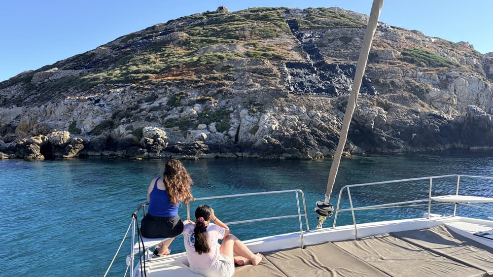two girls on a catamaran looking at the archaeological site of Keros