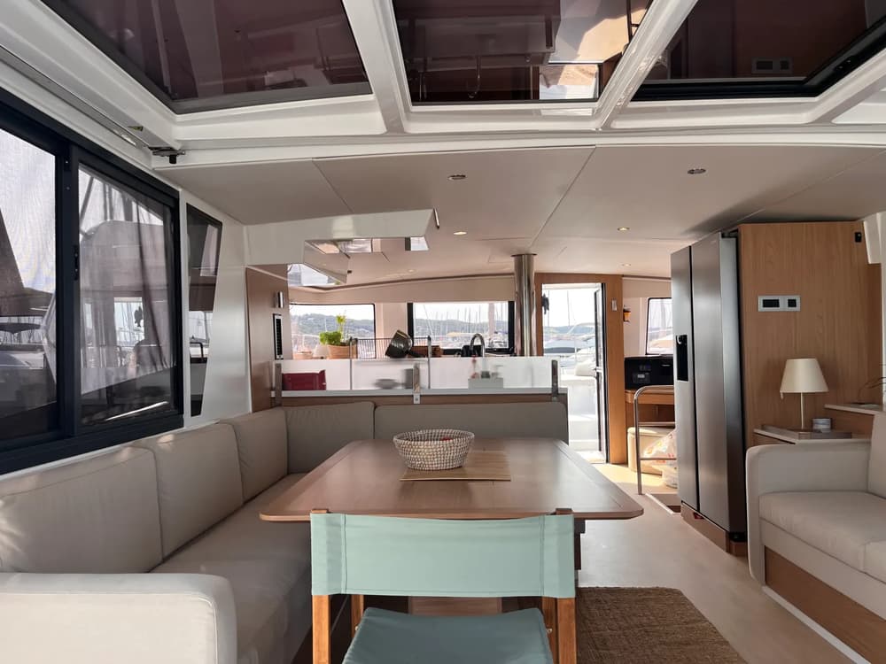 Interior view from inside the Bali 4.6 catamaran’s saloon, featuring a panoramic sliding window and direct access to the forward cockpit, highlighting the yacht’s unique open-space concept.