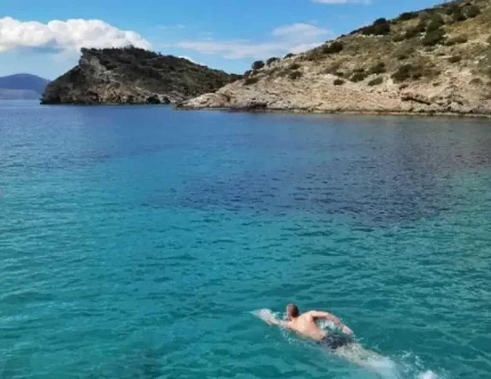 Man swimming in clear blue waters during a sailing holiday around Athens and the Saronic Gulf.
