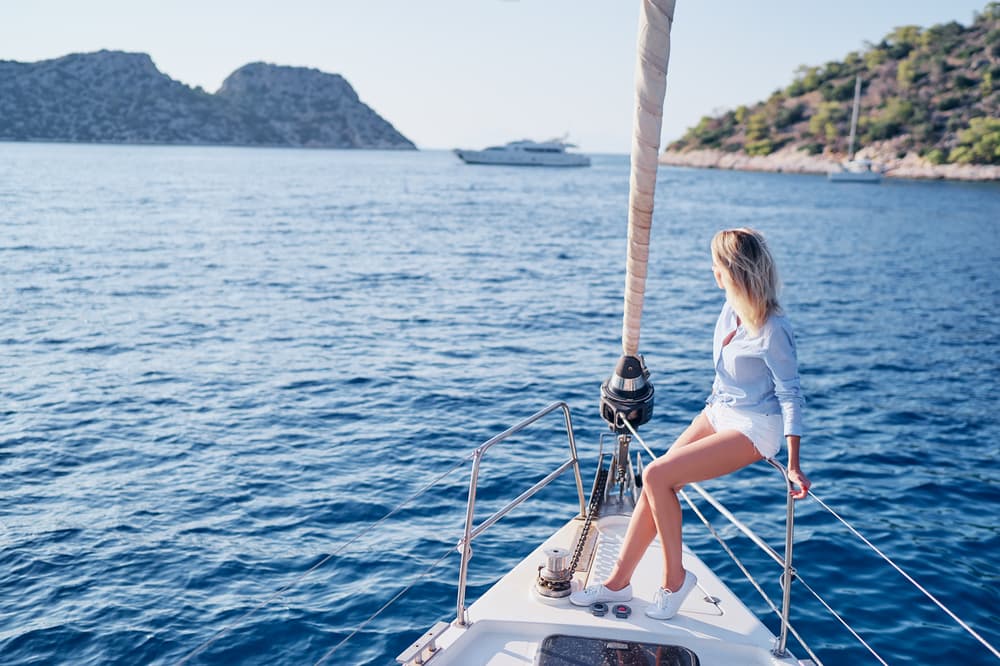 woman enjoying the view from the bow of a sailing yacht during a bareboat yacht charter in the Mediterranean