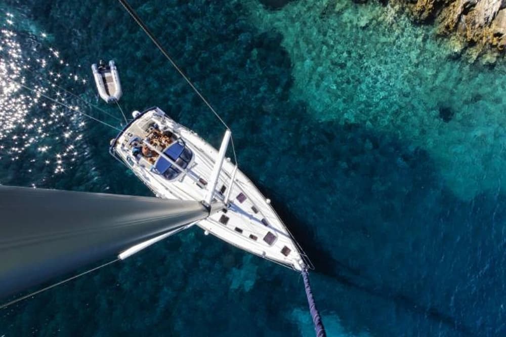 Aerial view of a luxury sailboat anchored in clear turquoise water, perfect for charter adventures.