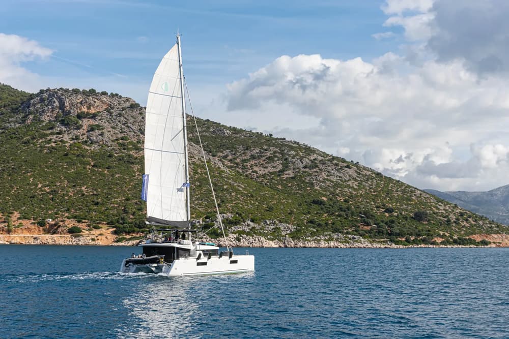 Modern catamaran sailing along a coastal landscape, showcasing stability and performance.