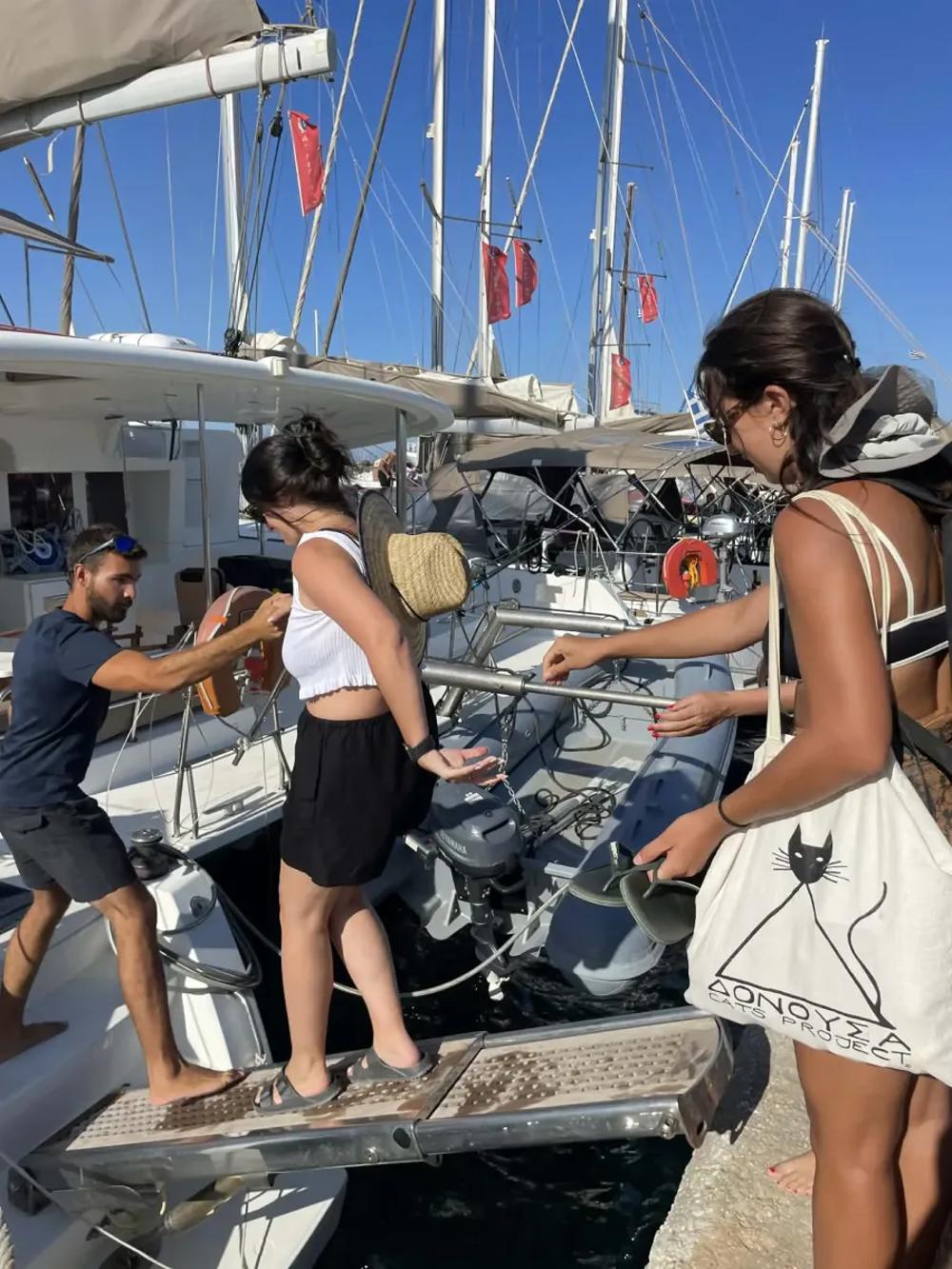 skipper helping yacht charter guests get on board a catamaran