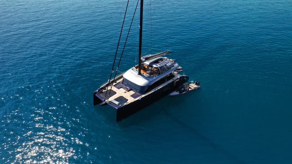 A sleek luxury catamaran anchored in pristine blue waters, offering a premium experience of a fully crewed yacht charter.