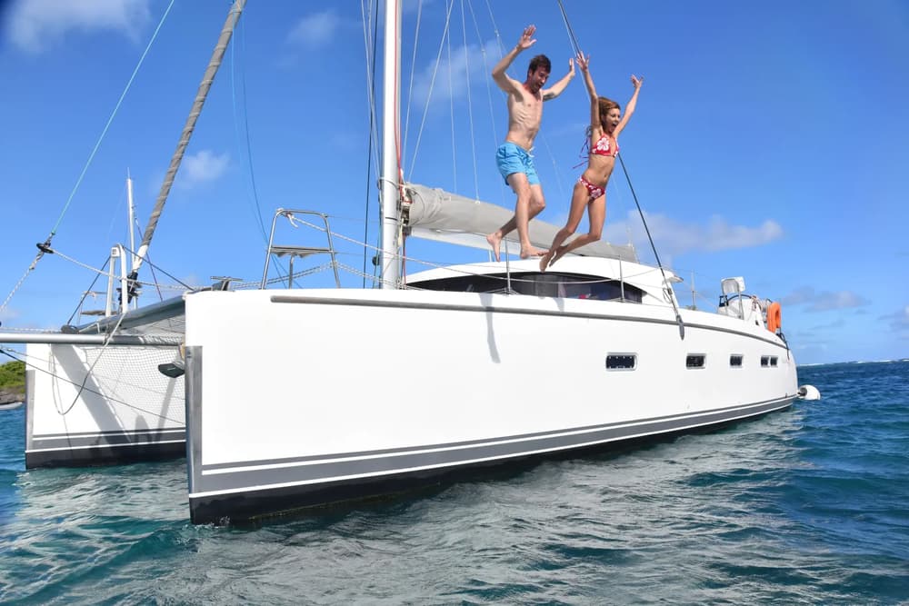 couple jumping off a boat sailing on a bareboat yacht charter