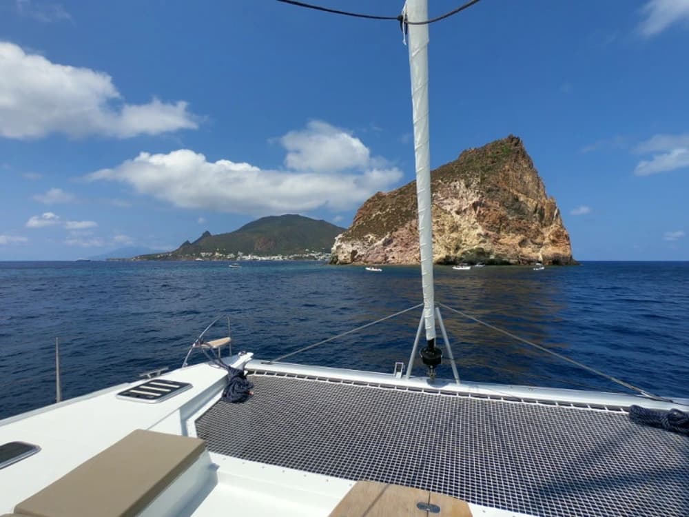 Catamaran anchored near the volcanic Aeolian Islands, showcasing unique destinations for sailing holidays in Italy.