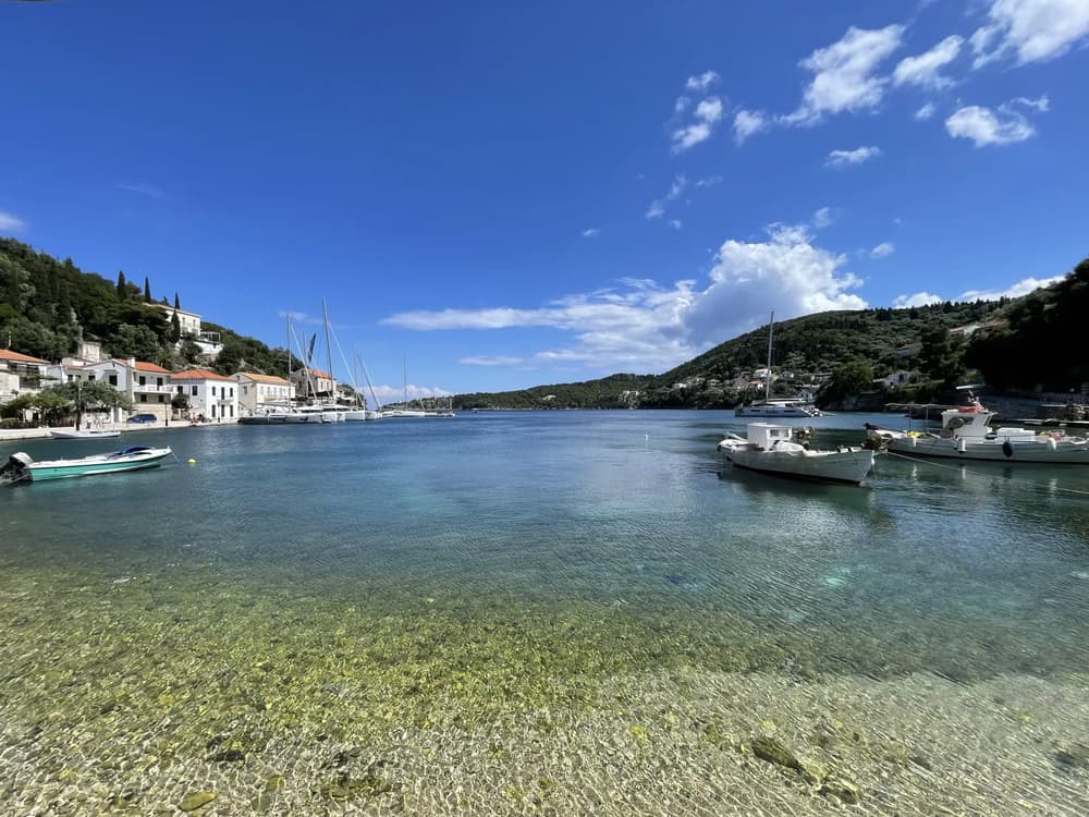 Crystal-clear waters and moored sailing yachts along the picturesque harbour of Kioni on Ithaca island.