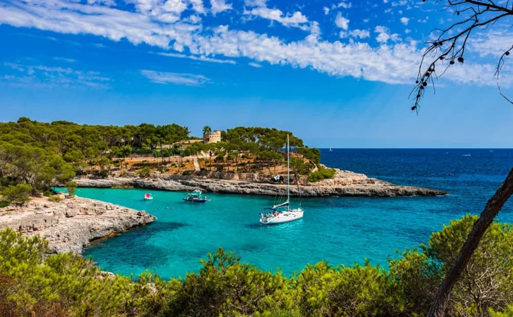 Secluded cove in Mallorca with sailboats anchored near the shore, ideal for sailing adventures in Spain.