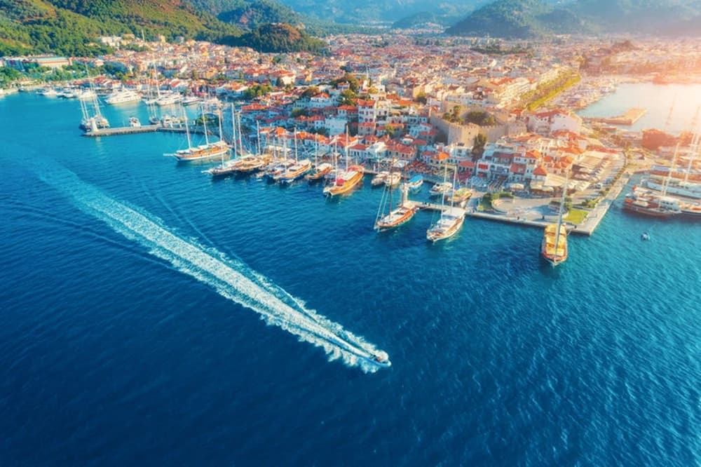 Aerial view of Marmaris marina with yachts and a vibrant coastal town, a highlight of Turkey's sailing adventures.
