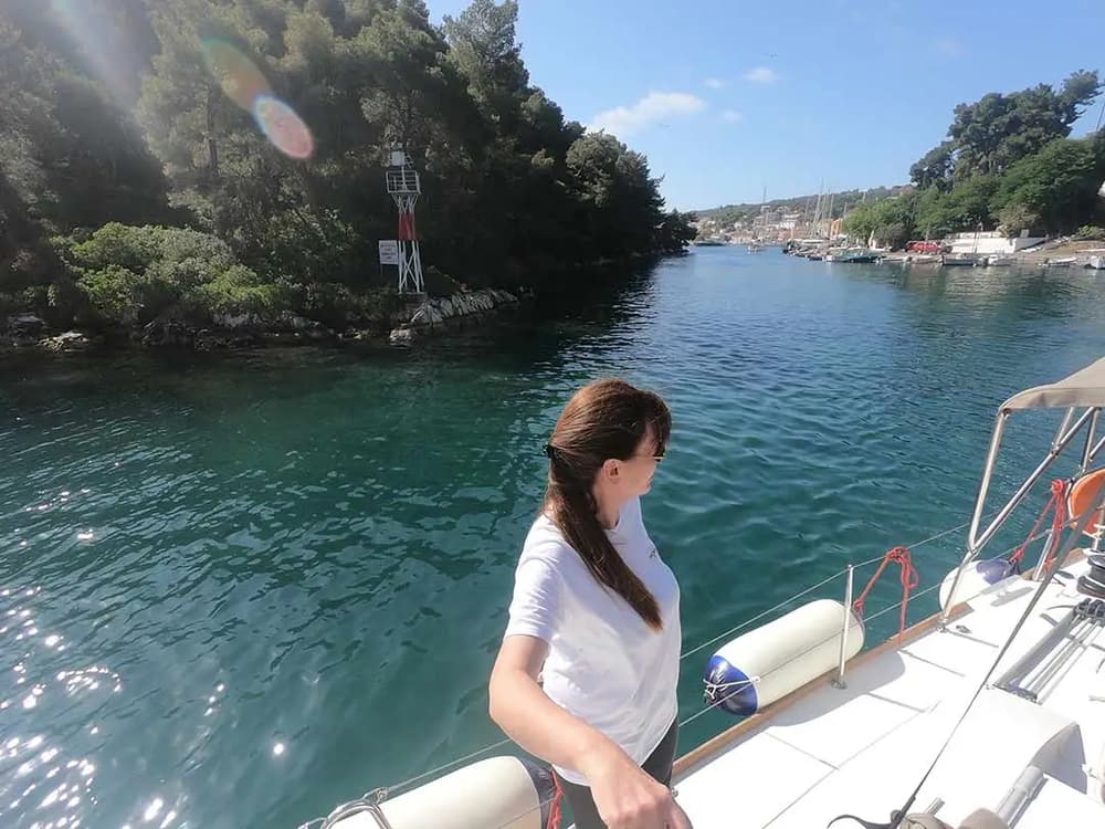 Sailor enjoying the scenic Ionian coastline on a yacht charter from Athens to Corfu.