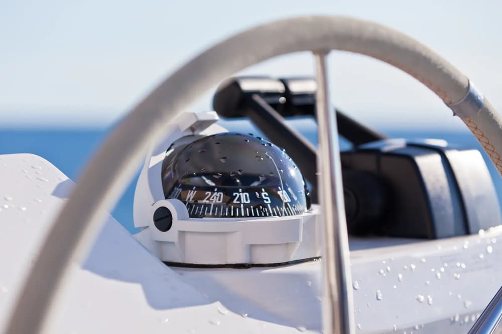 A precise navigation compass with water droplets, reflecting the direction and adventure of a skippered yacht charter experience.