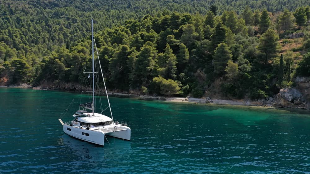 yacht on anchor in idyllic bay with mountain background