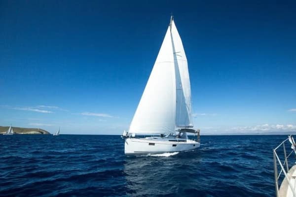 Wide shot of a modern sailboat navigating the open sea, showcasing a top-rated model for charter.
