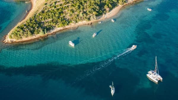 Aerial view of a serene sailing destination with catamarans and yachts, highlighting the best time to sail for calm waters and sunny weather.