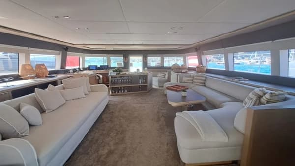 Expansive saloon area of the Lagoon 78, showcasing plush seating, panoramic windows, and a fully stocked bar—perfect for luxury yacht charters and high-end sailing holidays.