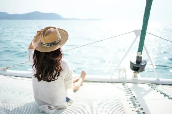 Woman relaxing on a catamaran during an overnight sailing trip, enjoying the open sea—your ultimate guide to overnight boating adventures.