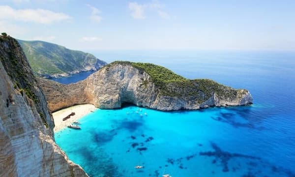 Aerial view of Navagio Beach (Shipwreck Beach) in Zakynthos, Greece, with turquoise waters and sailing yachts—perfect for an Ionian yacht charter holiday.