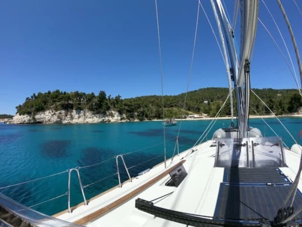 Bow view of a sailing yacht in a serene turquoise bay, reflecting the allure and affordability of yacht charters.