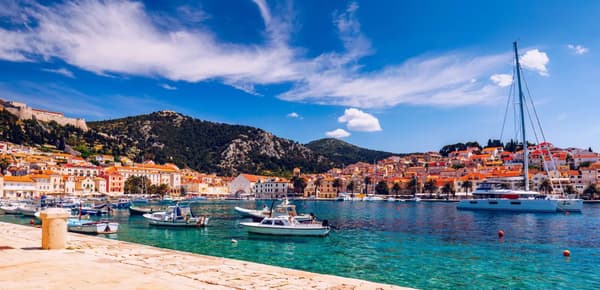 A scenic view from a sailing yacht docked in a serene marina surrounded by lush greenery, showcasing the charm of sailing holidays in Greece or Croatia.