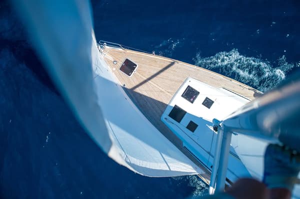Aerial view of a sailing yacht gliding through deep blue waters, showcasing wind-powered movement as a symbol of eco-friendly and sustainable yachting.