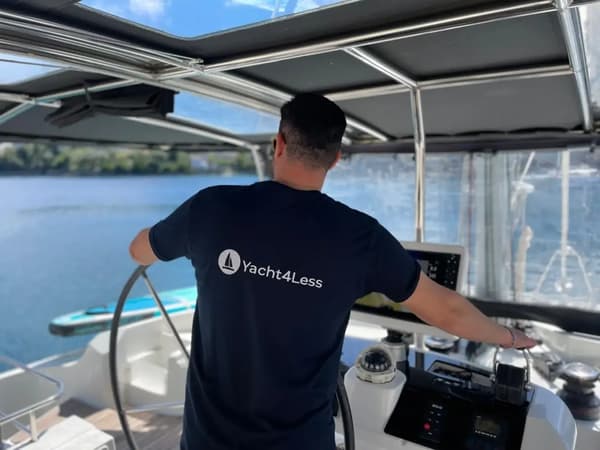 A professional skipper from Yacht4Less steering a catamaran during a skippered yacht charter, ideal for relaxed sailing holidays with a captain in the Mediterranean.
