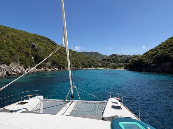 Tranquil beach in Corfu with boats floating in the calm waters. Ideal for a Greece sailing holiday, exploring Corfu’s coastline, and discovering top Ionian sailing destinations with Yacht4Less.