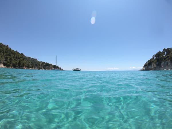 Turquoise waters and anchored yachts in a secluded bay in the Sporades Islands, ideal for tranquil sailing holidays in Greece